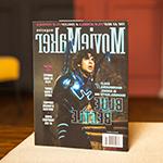 A copy of MovieMaker Magazine sits on a table. An actor in a Blue Beetle costume is on the cover. The headline “The 25 Best Film Schools & Coolest Film Festivals” runs across the top.